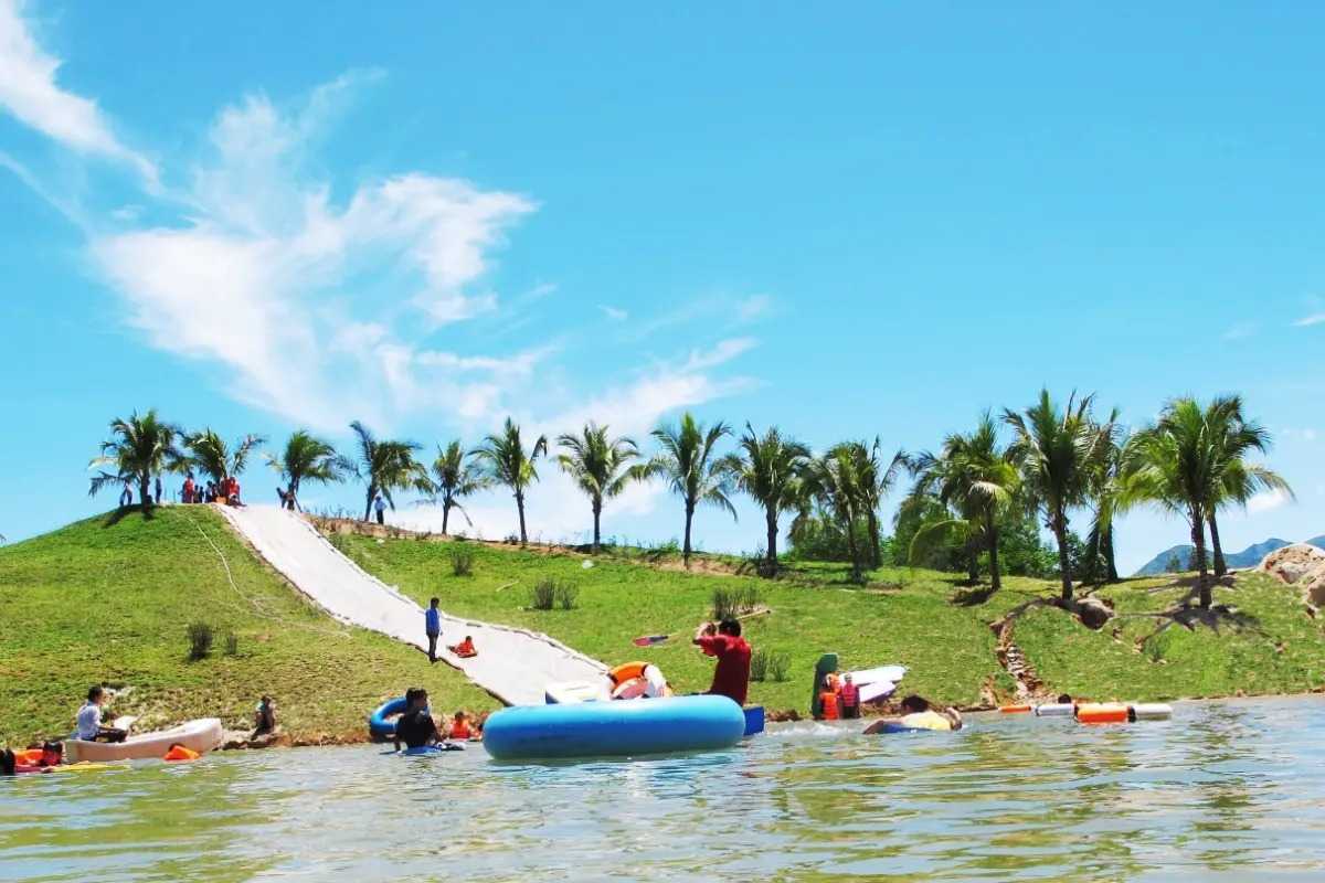 Inflatable games and stream slide at Waterland Guests enjoy inflatable rides and slide down a grass slope into the lake at Waterland Thach Lam.