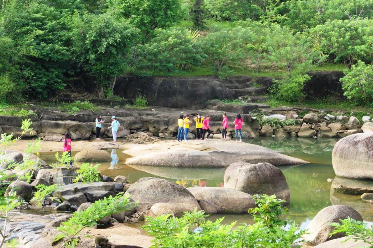Nature walking area at Waterland Thach Lam Visitors exploring rocks and greenery in a calm stream area of Waterland Thach Lam.
