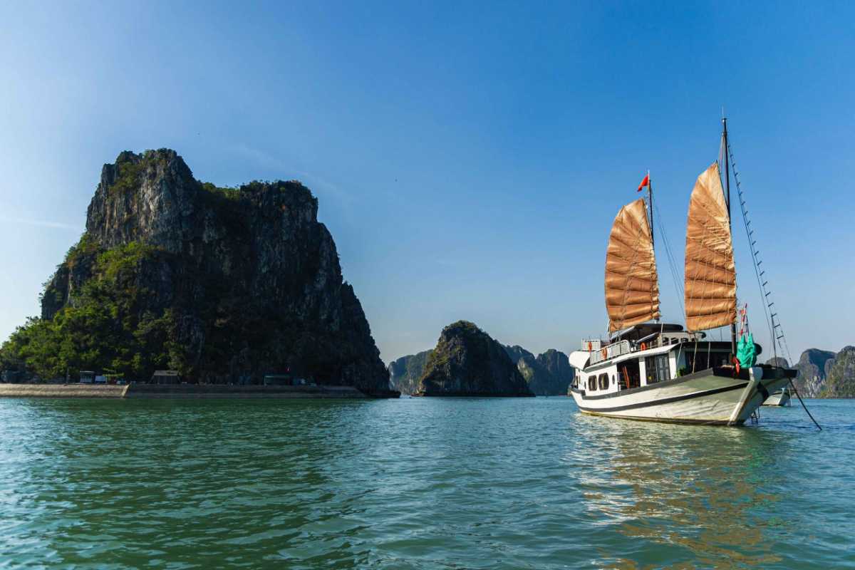 Calm waters surrounding Xep Islet Halong Bay with dramatic limestone karsts under a clear blue sky.