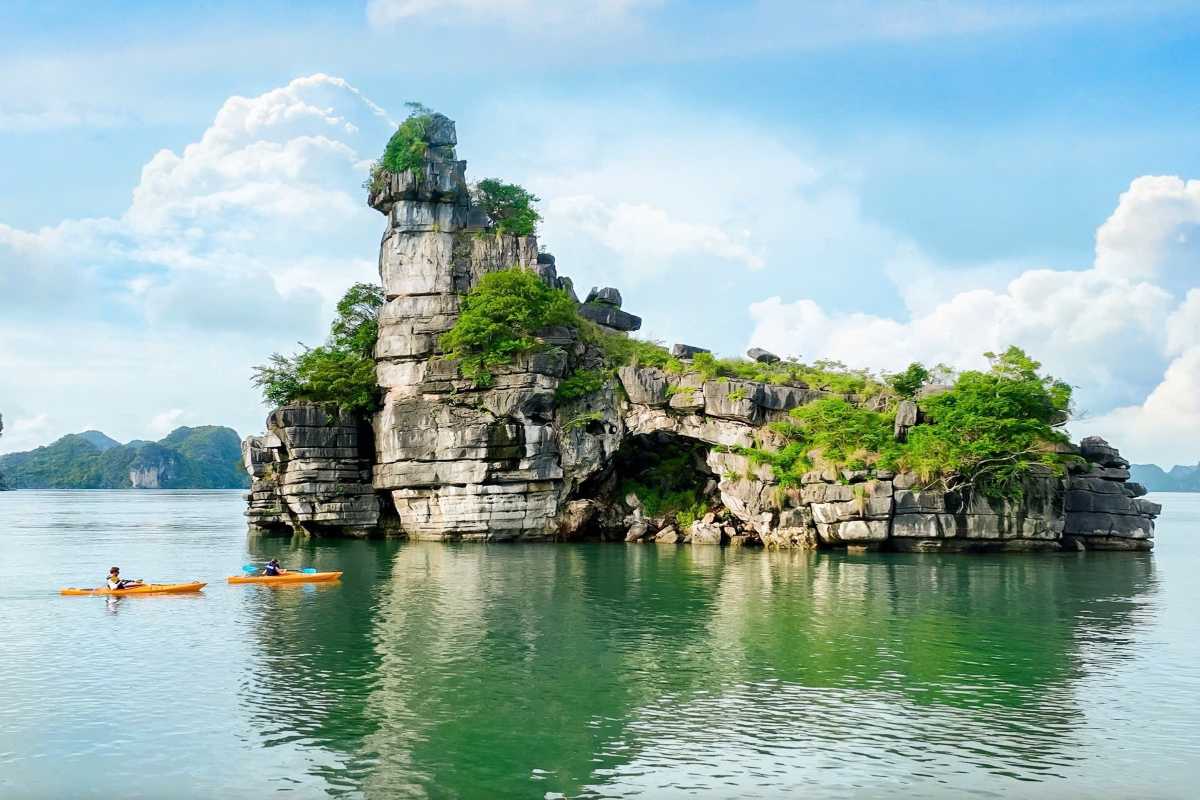 Kayakers exploring calm green waters near Xep Islet Halong Bay, surrounded by limestone cliffs