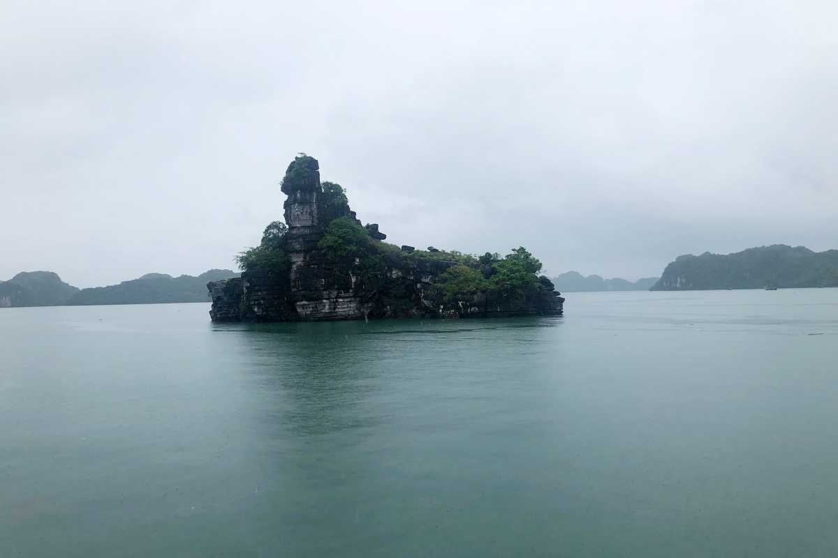 Xep Islet Halong Bay showcasing a dramatic limestone karst island with lush greenery under cloudy skies