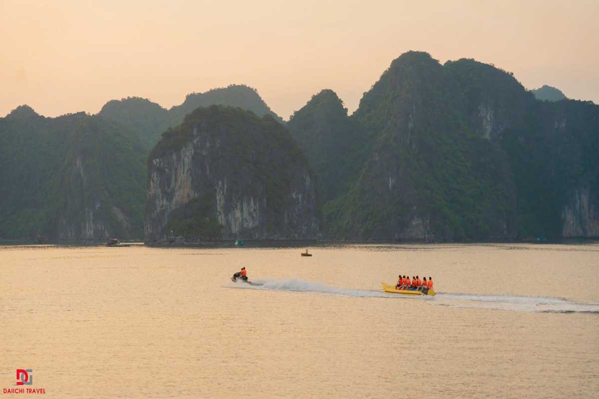 Traditional junk boat with brown sails cruising the emerald waters of Xep Islet Halong Bay amidst limestone islands.