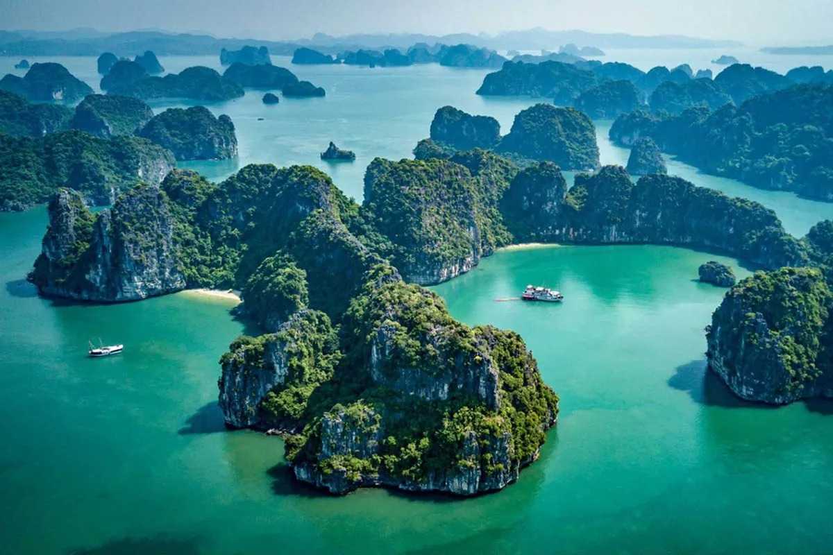 Traditional junk boats cruising the emerald waters near Xep Islet Halong Bay