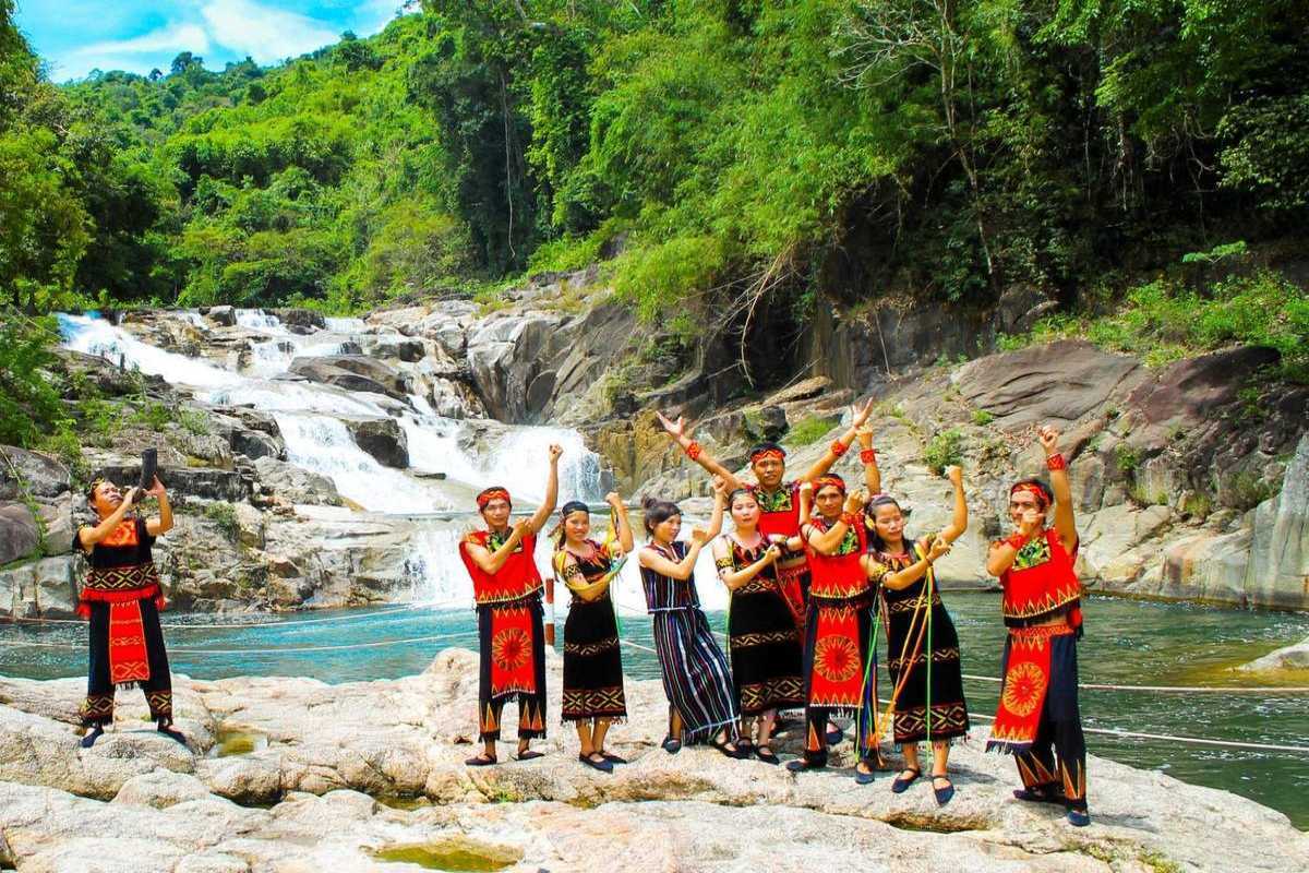 Raglai cultural performance at Yang Bay Group of Raglai performers in traditional dress posing in front of the waterfall at Yang Bay