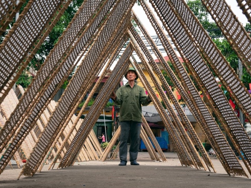 Bamboo Mats Drying in Tho Ha Village A man setting up bamboo mats in Tho Ha Village, Bac Giang, showcasing the local handicraft