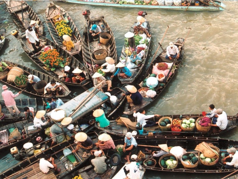 Cai Be Floating Market in Tien Giang - Bustling River Market A vibrant image of Cai Be Floating Market in Tien Giang featuring boats filled with fruits, vegetables, and local products.