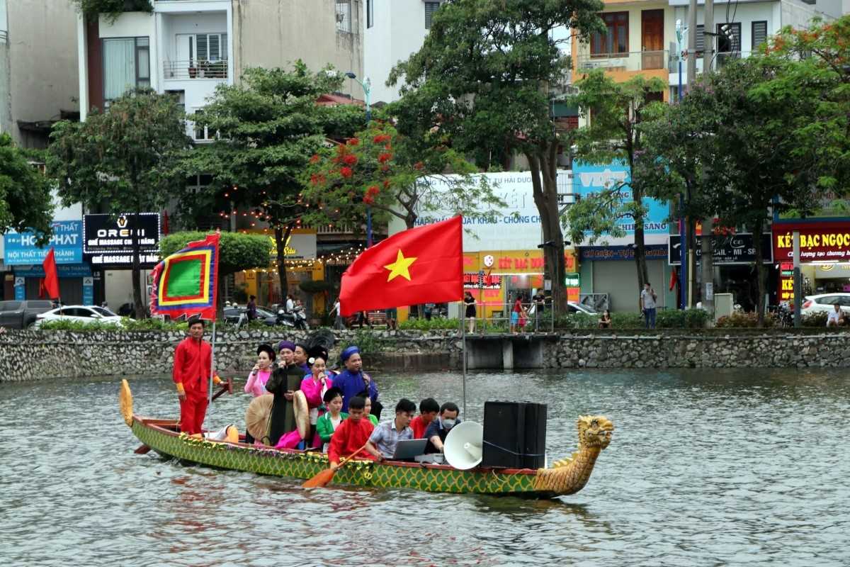 Traditional Cheo singing boat performance in Hai Duong Spring Festival with performers in colorful costumes and a large Vietnamese flag.