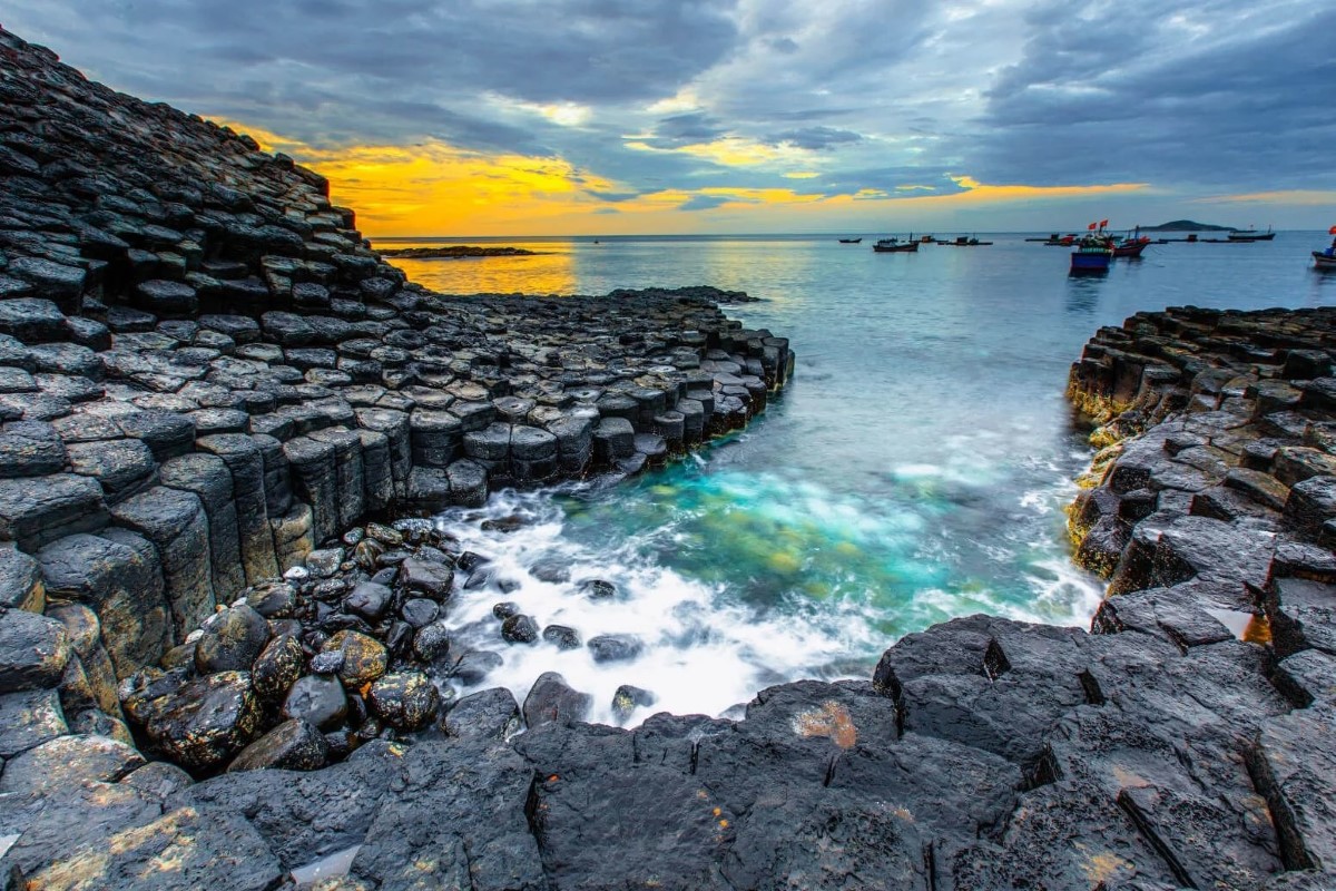 Da Dia Reef - Vietnam's Natural Wonder Hexagonal basalt columns of Da Dia Reef in Phu Yen, Vietnam, with vibrant sunset sky and calm sea.