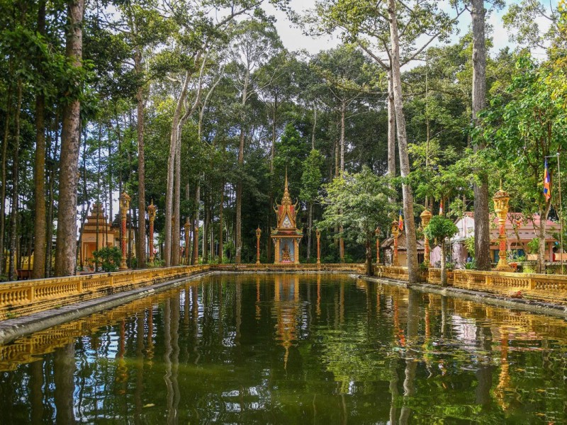 Golden Khmer Temple by Pond in Tra Vinh Golden Khmer temple reflecting on a pond in Tra Vinh, with intricate carvings.