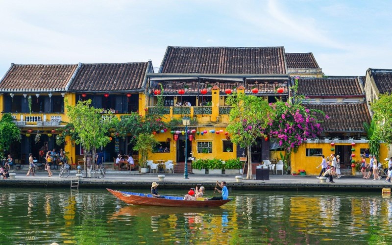 Hoi An Riverside with Historic Architecture Hoi An Ancient Town riverside with historic architecture and tourists enjoying boat rides.
