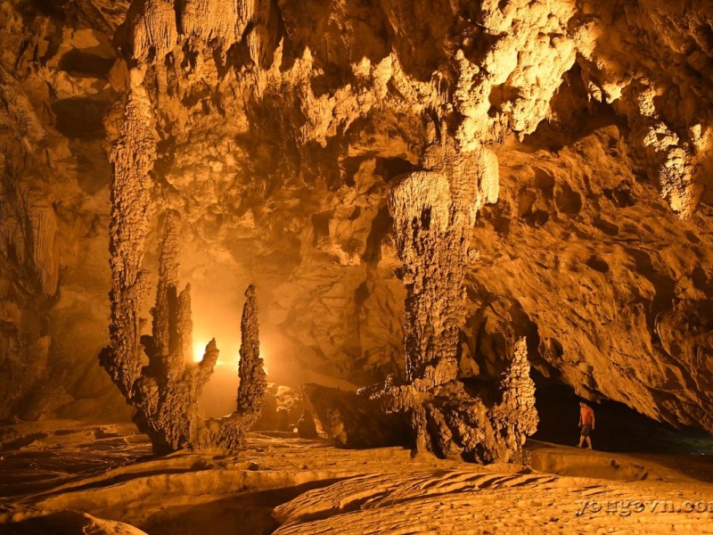 Nguom Ngao Cave Adventure An adventurer exploring the depths of Nguom Ngao Cave in Cao Bang, surrounded by limestone formations.