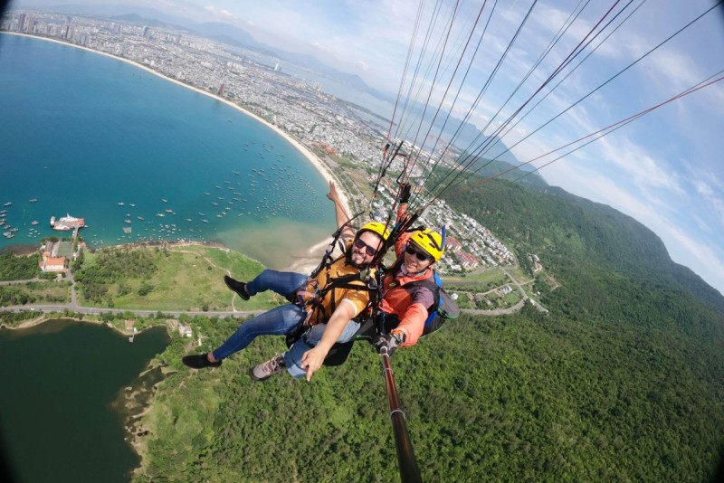 Paragliding Adventure at Son Tra Peninsula - Da Nang Paragliders soaring above Son Tra Peninsula in Da Nang, Vietnam with scenic views of the coastline and greenery.