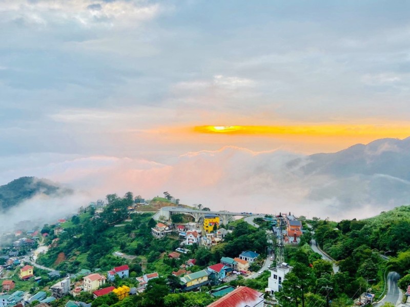 Scenic View of Tam Dao at Sunrise Sunrise view over the mountainous town of Tam Dao, with colorful houses and a cloud-filled valley.
