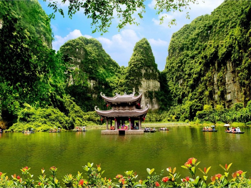 Tam Coc - Scenic Views of Ninh Binh's River and Cliffs Breathtaking view of Tam Coc river in Ninh Binh, surrounded by lush greenery and limestone mountains.