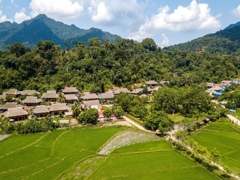 Traditional Stilt Houses in Tuyen Quang's Lam Binh District Aerial view of traditional stilt houses in Tuyen Quang's Lam Binh District, nestled in green rice fields.