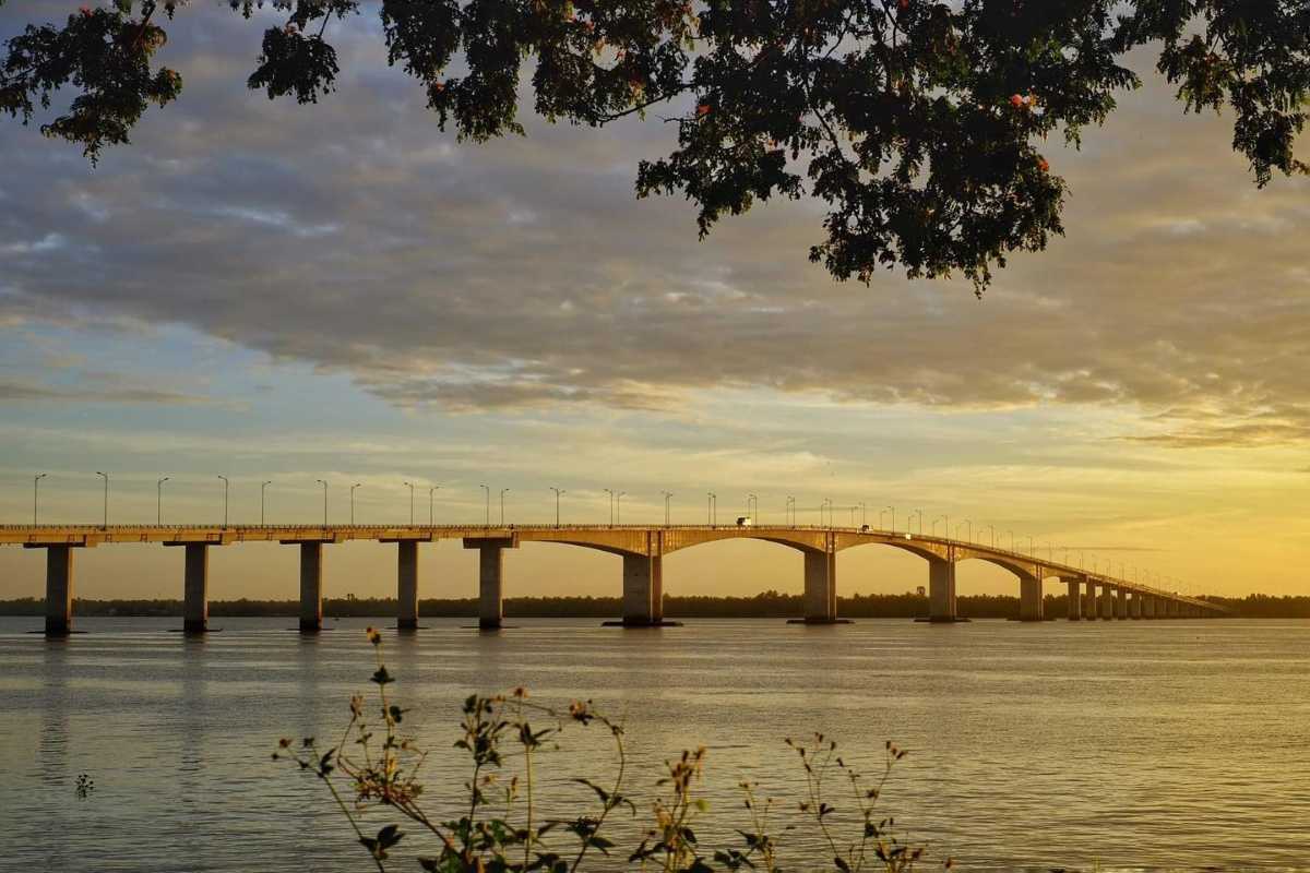 Sunset view of bridge over Mekong River Golden hour view of a large bridge arching over the calm Mekong River during sunset in Vinh Long