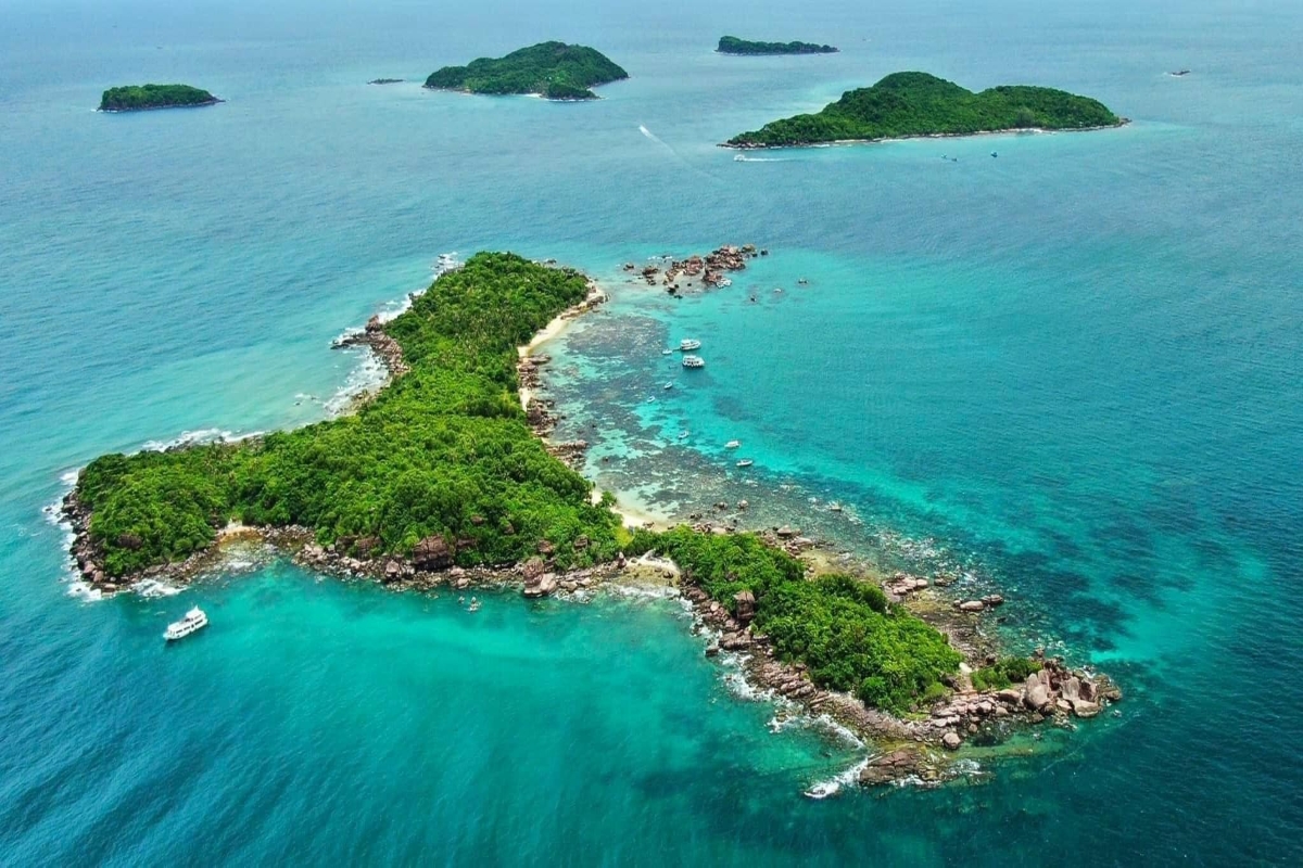 Drone shot of lush Gam Ghi Island surrounded by coral reefs and emerald water in Phu Quoc