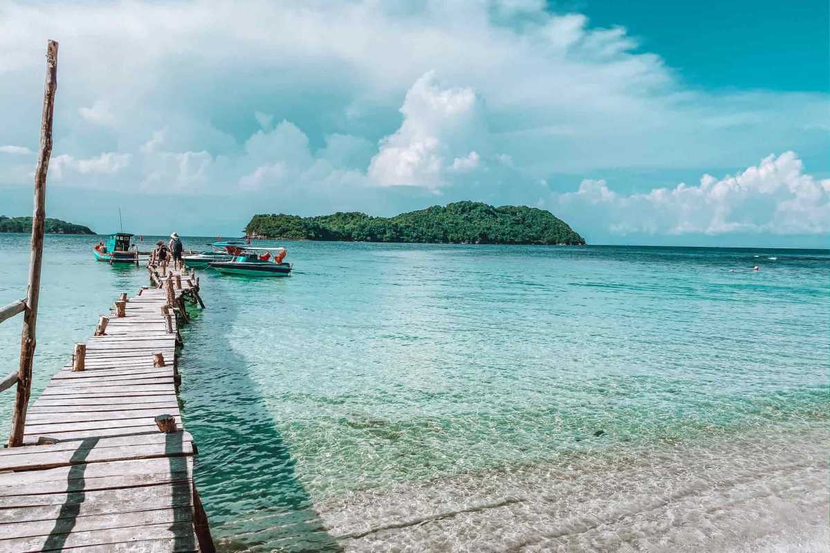 Bird's eye view of May Rut Trong Island with beach bars, boats, and lush forest in Phu Quoc.