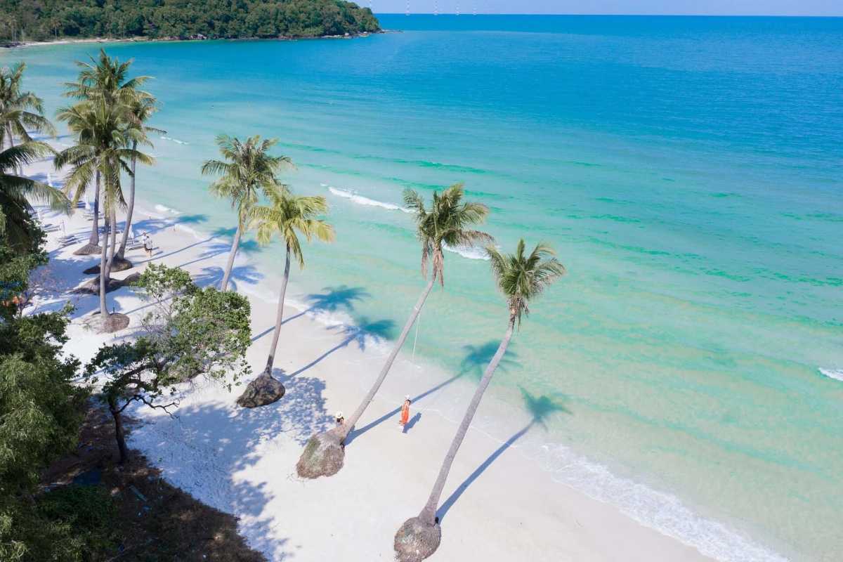 Overhead view of Bai Sao Beach with leaning palm trees, turquoise waters, and white sand on a sunny day in Phu Quoc.