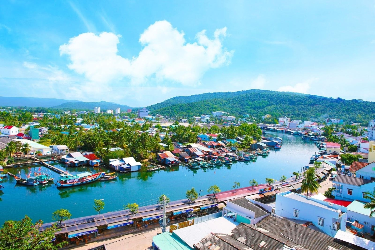 Vibrant rooftops and riverboats of Duong Dong town captured under bright daylight, close to squid fishing sites.