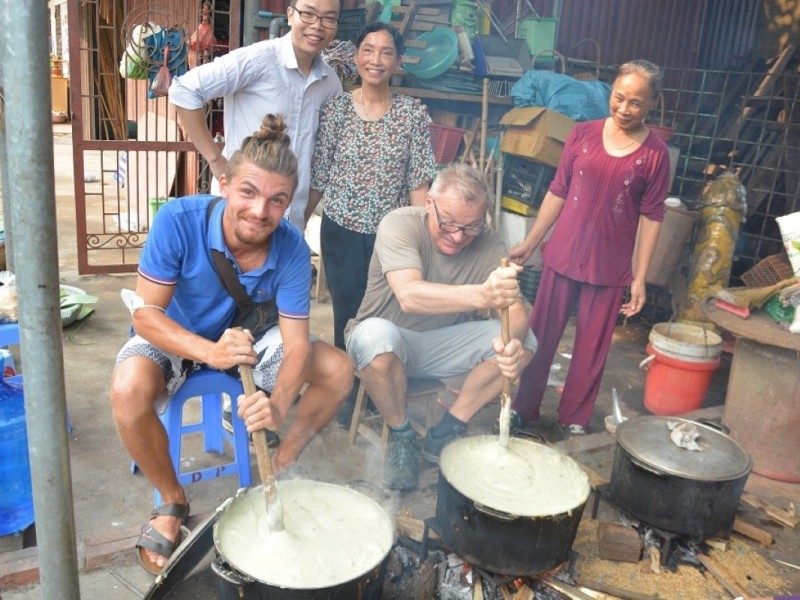 Tourists cooking traditional dishes with locals in a village setting.